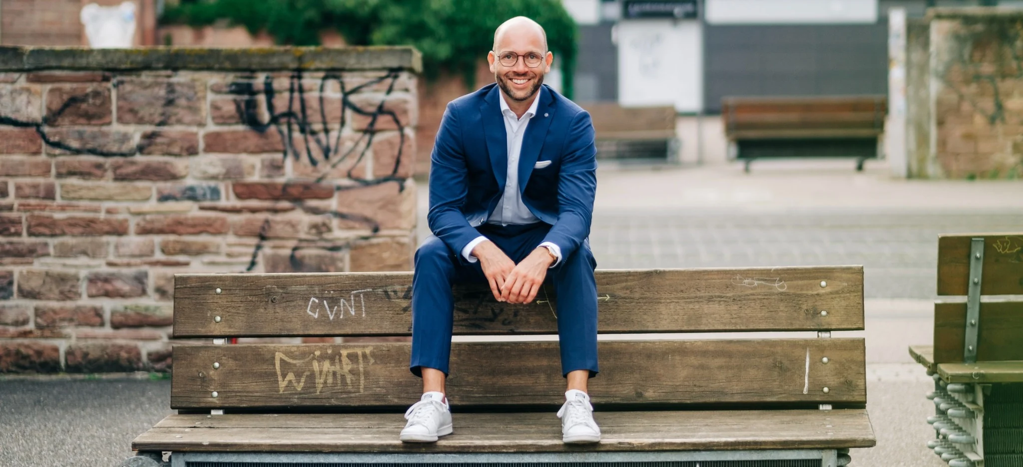 Andreas Eisinger sitzt im blauen Anzug auf einer Bank